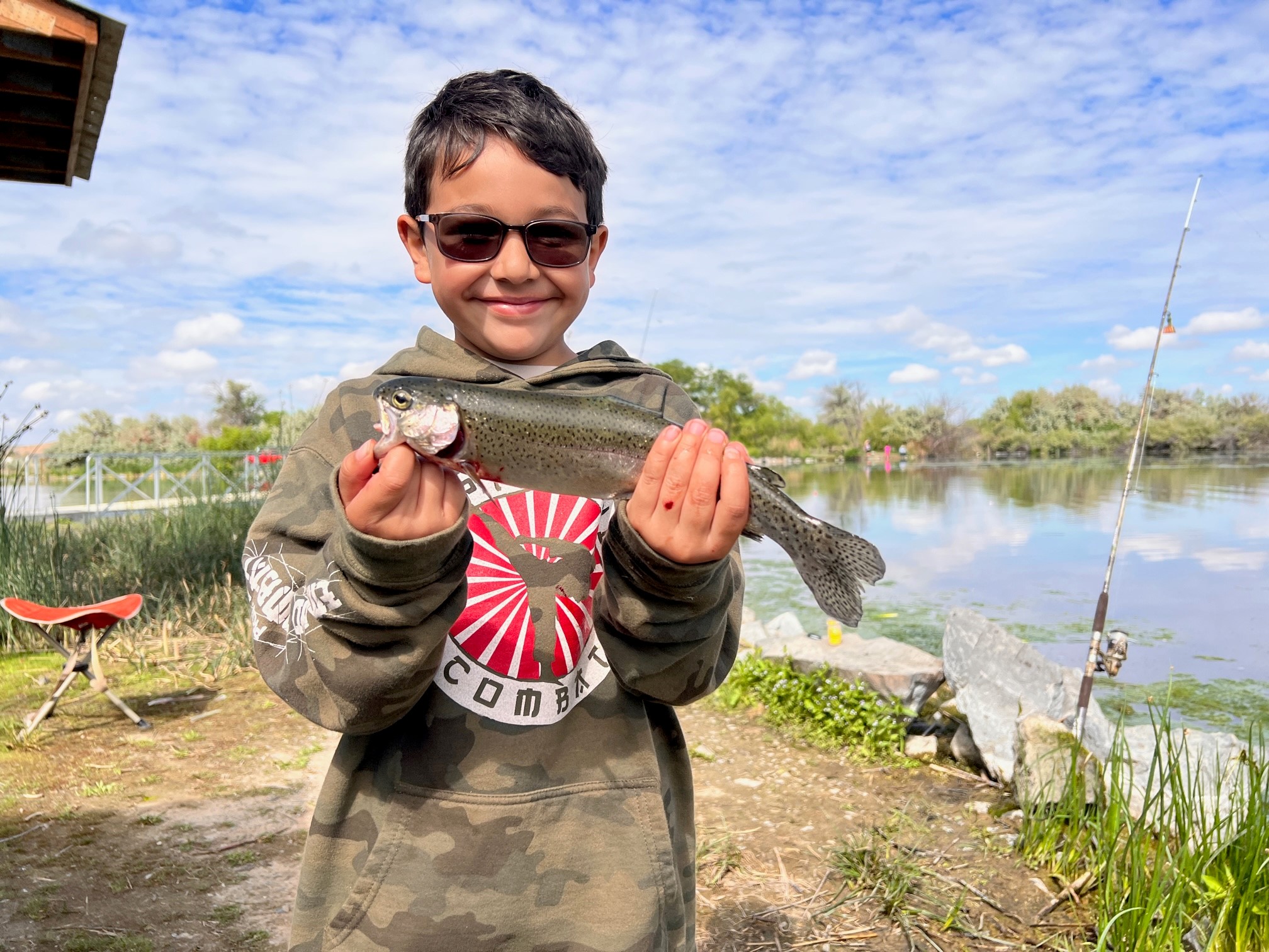 A young boy with a rainbow trout caught at Free Fishing Day, Riley Pond, June 2023