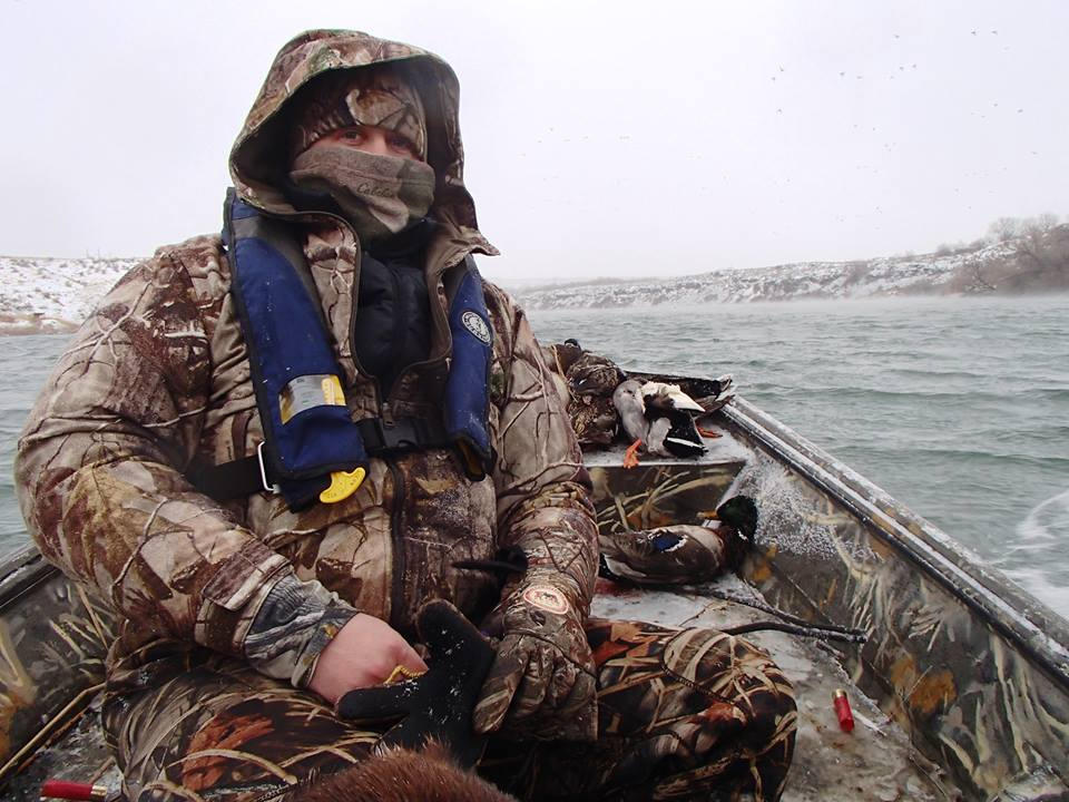 Duck hunter in camo sitting in duck boat in winter